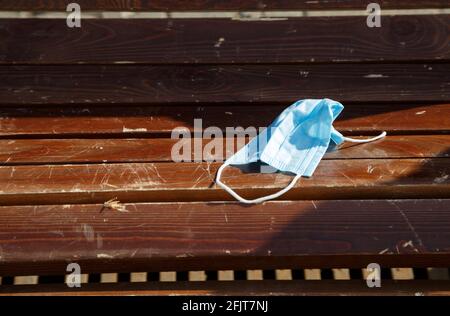 Photo of throwed used protective mask on the wooden bench Stock Photo