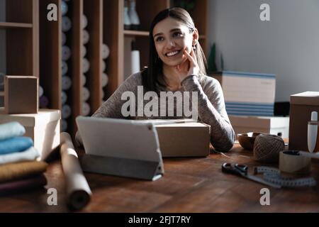 Indian mixed-race female seller using tablet checking ecommerce clothing store orders Stock Photo