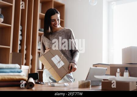 Indian mixed-race female seller using tablet checking ecommerce clothing store orders Stock Photo