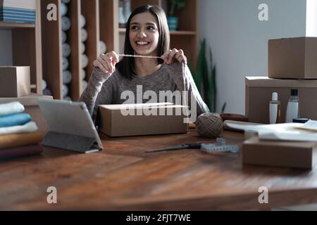 Indian mixed-race female seller using tablet checking ecommerce clothing store orders Stock Photo