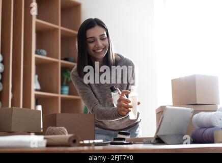 Indian mixed-race female seller using tablet checking ecommerce clothing store orders Stock Photo