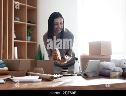 Indian mixed-race female seller using tablet checking ecommerce clothing store orders Stock Photo