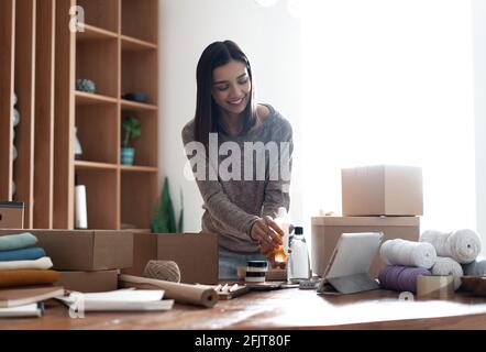 Indian mixed-race female seller using tablet checking ecommerce clothing store orders Stock Photo