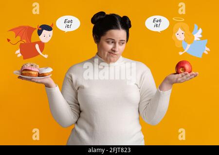 Hungry overweight woman on diet making choice between donuts and apple, tempted by devil and supported by angel Stock Photo