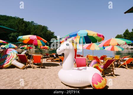Inflatable white unicorn on the royal beach in Przno against the backdrop of green trees Stock Photo
