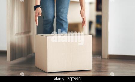 Unrecognizable person picking cardboard box up from the floor Stock Photo