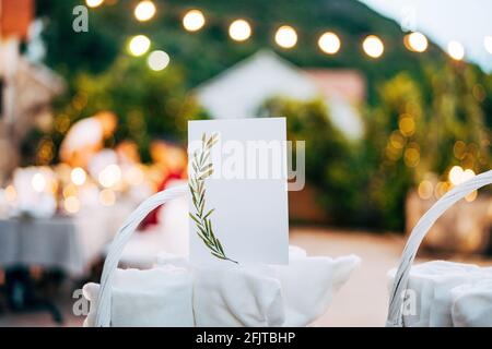 Blank card with ornament stands on rolled towel in white wicker basket on table Stock Photo