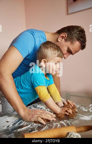 Father's Day concept. Father and son together bakes cookies at home. Homemade baking. Family time at home. Holiday mood concept. Stock Photo
