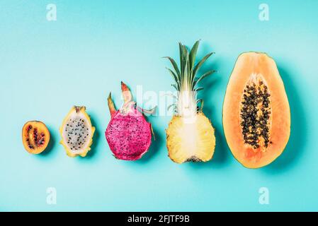 Creative layout made of exotic fruits - papaya, pineapple, dragon fruit, pitahaya, tamarillo fruit on blue background. Flat lay. Top view. Copy space Stock Photo