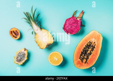 Creative layout made of exotic fruits - papaya, pineapple, dragon fruit, pitahaya, tamarillo fruit on blue background. Flat lay. Top view. Copy space Stock Photo