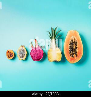 Creative layout made of exotic fruits - papaya, pineapple, dragon fruit, pitahaya, tamarillo fruit on blue background. Flat lay. Top view. Copy space Stock Photo