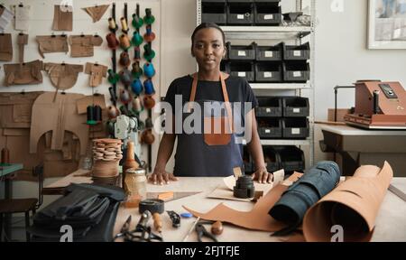 Young African female leather worker standing by a work table Stock Photo