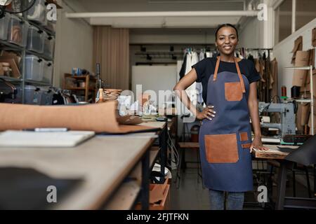 Smiling African female leather worker standing in her studio Stock Photo