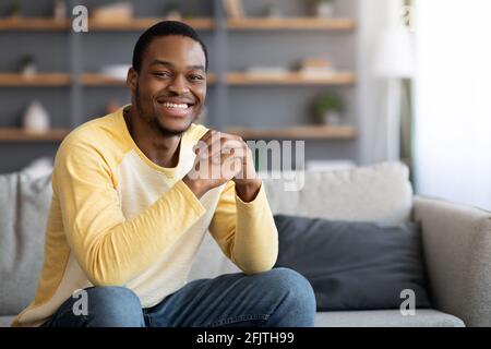 Closeup of positive young black man chilling on sofa Stock Photo