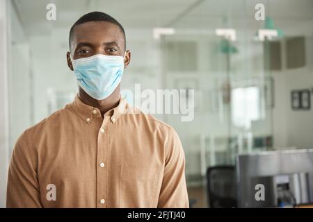 African businessman standing in his office wearing a face mask Stock Photo