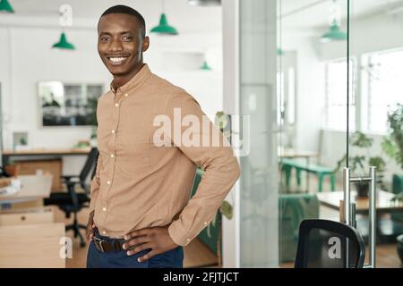 Smiling young African businessman standing alone in an office Stock Photo