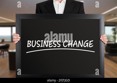Businessman holds a big signboard with business change message. Change in business announcement. Stock Photo