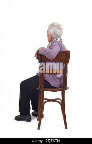 an older woman sitting in profile and looking back on white background Stock Photo