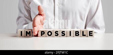 Businessman hand changes the word impossible into possible written on wooden cubes. Stock Photo