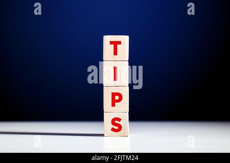 The word tips written on tiered wooden cubes against blue background. Stock Photo