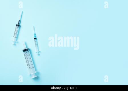 Syringes of different size on blue background. Injections and vaccination concept. Health protection medicine equipment during quarantine Coronavirus Stock Photo
