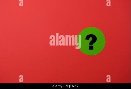 Question mark on a green circle paper with red background. Stock Photo