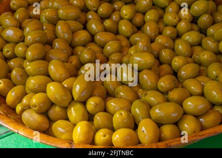 Green pickled Olives at the weekly market in french province. Background of olives in a bowl, close up. Stock Photo