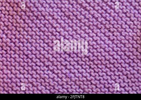 close up detail of purple pink knitted square for sewing together to make a blanket Stock Photo