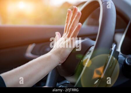 female hand presses the horn on the steering wheel of a modern car. no face Stock Photo
