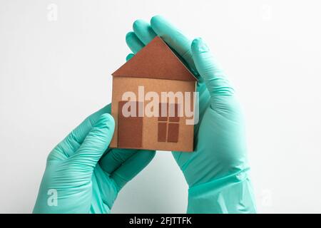 Hands in gloves holding a paper house on white background Stock Photo