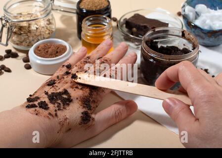 Womans hands testing chocolate face and body scrub. Close up. Home beauty concept. Stock Photo