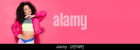 sporty and curly african american woman posing on pink, banner Stock Photo