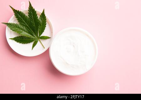 medicinal medicine cbd infused topical lotion for pain and inflammation relief on a pink background, cannabis plant on lotion Stock Photo