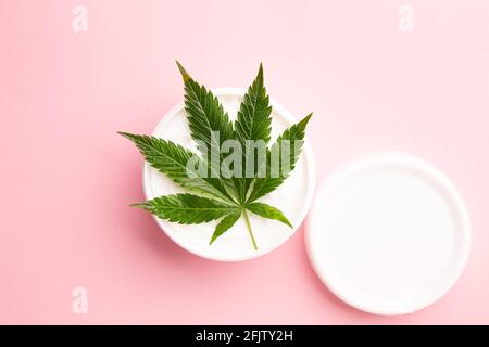 medicinal medicine cbd infused topical lotion for pain and inflammation relief on a pink background, cannabis plant on lotion Stock Photo