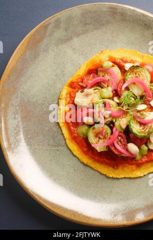 A STILL LIFE OF BRUSSEL SPROUT TACOS,WITH BRUSSEL SPROUTS, CHARRED AND RAW TOMATOES, PICKLED ONIONS, ADOBO SAUCE, SALSA VERDE, PEANUTS,  ON A CORN TOR Stock Photo
