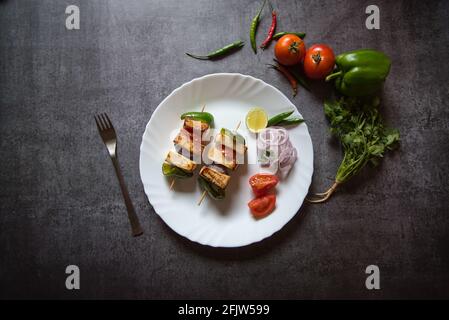 Top view of paneer tikka on a white plate along with salad and vegetable condiments Stock Photo
