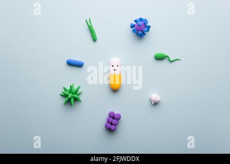 funny pill for infection. capsule with eyes, surrounded by viruses and bacteria on a blue background. medical concept antibacterial. Stock Photo