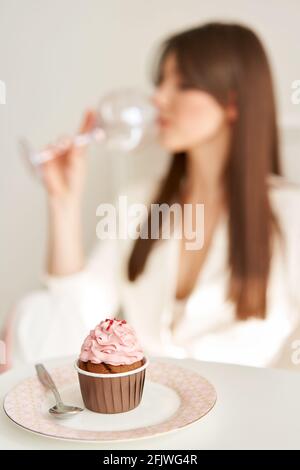 woman eating pink cupcake on the plate, by little spoon. Stock Photo