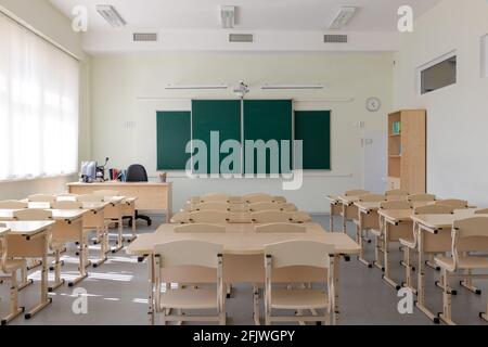 empty school class before final exams. desks and chairs are neatly arranged in three rows. overall plan Stock Photo