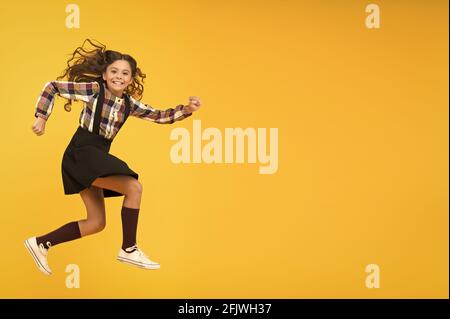 Happy childrens day. Jump concept. Break into. Feel inner energy. Girl with long hair jumping on yellow background. Carefree kid summer holiday. Time Stock Photo