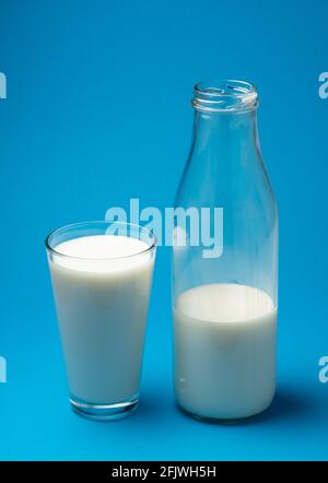 Glass of fresh milk and bottle of milk isolated on blue background. Stock Photo