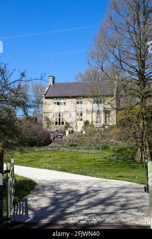 Pretty detached cottage and garden with a gated drive entrance in The Cotswolds village of Compton Abdale in Gloucestershire UK in springtime Stock Photo