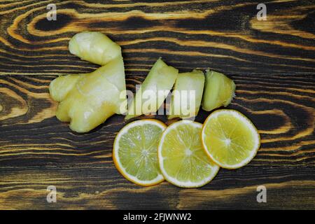 chopped ginger root with lemon on wooden background photographed from above Stock Photo