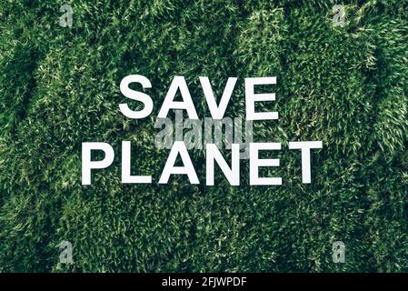 Inscription Save planet on moss, green grass background. Top view. Copy space. Banner. Biophilia concept. Nature backdrop Stock Photo