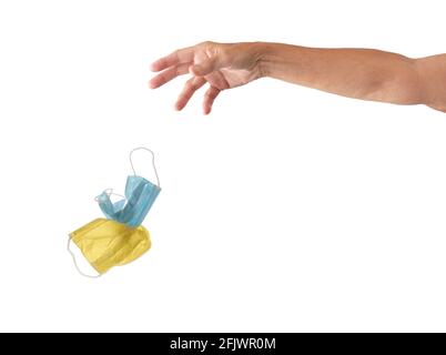 Hand and arm discarding two Covid face masks, isolated on white with copy space or to be easily extracted and placed into another image. Stock Photo