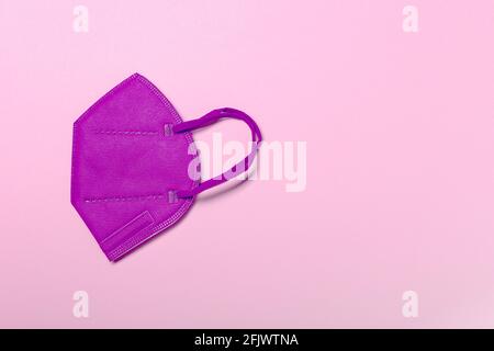 Pink KN95 or N95 FFP2 mask for protection and corona virus on pastel pink background. Anti pollution concept. copy space, from above. Stock Photo