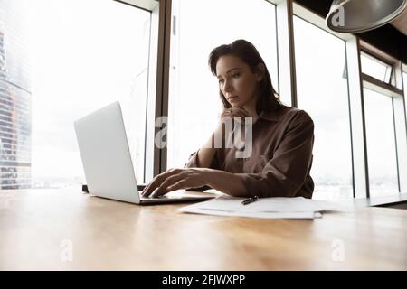 Pensive Caucasian female employee work on laptop Stock Photo