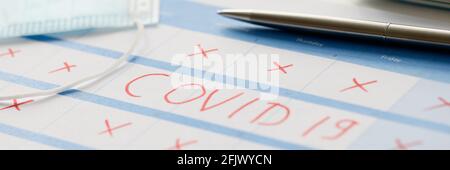 Pen lying on table with calendar with red strikethrough dates during covid19 pandemic Stock Photo