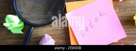 Crumpled multicolored pieces of paper and magnifying glass lying on table Stock Photo
