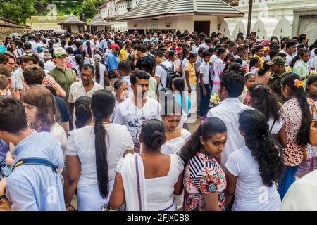 KANDY, SRI LANKA - JULY 19, 2016: White clothed Buddhist devotees wait in a queue at the entrance to the Temple of the Sacred Tooth Relic during Poya Stock Photo